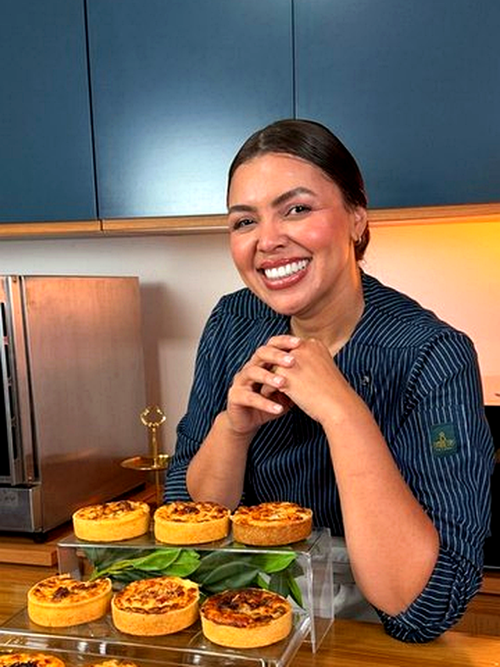 Chef Geicy Galindo sorrindo na cozinha, de jaleco